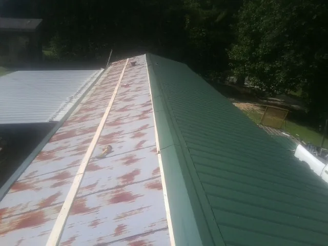 Old rusted panels beside newly installed green metal roofing — Wind Damage Roof Repair by Roofing Brothers in Dupont