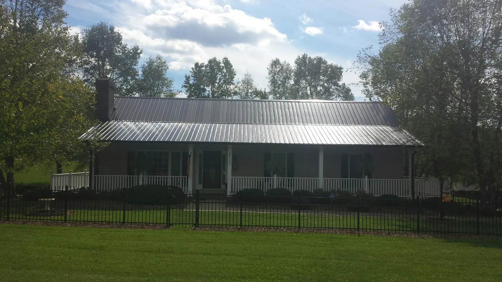 Gray metal roof on a brick ranch with a full width front porch — Gutter Guard Installation work by our crew in Dupont