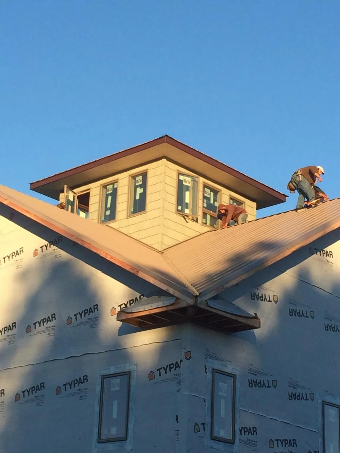 Roofers working around a rooftop cupola on a new metal roof at sunset — Roof Waterproofing in Dupont by Roofing Brothers